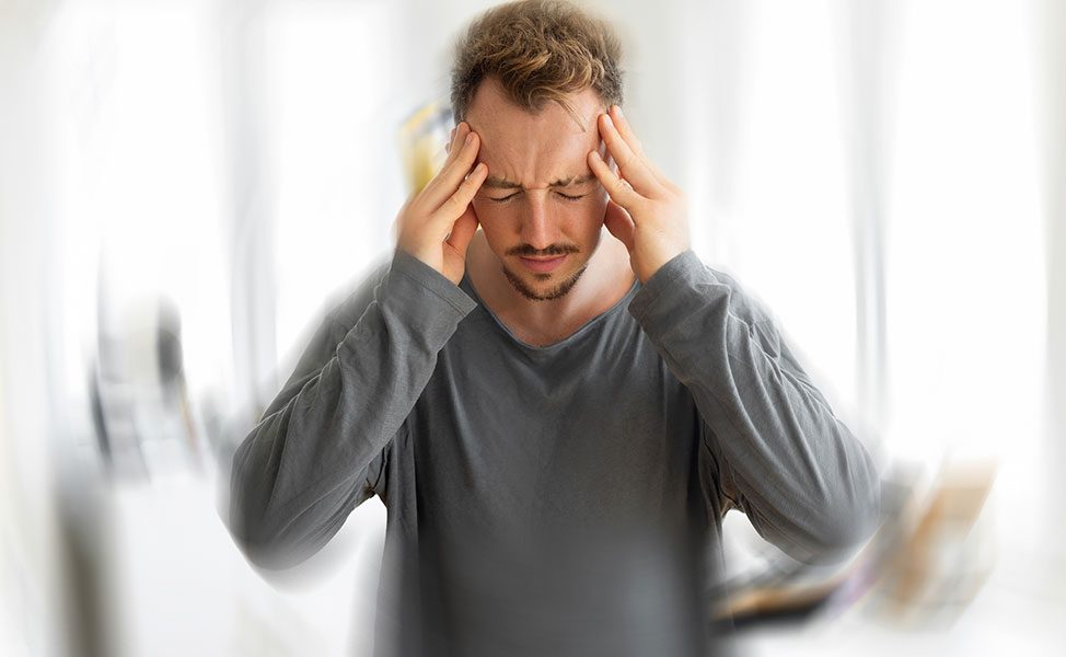 Jovem sentindo uma vertigem com a mão na cabeça